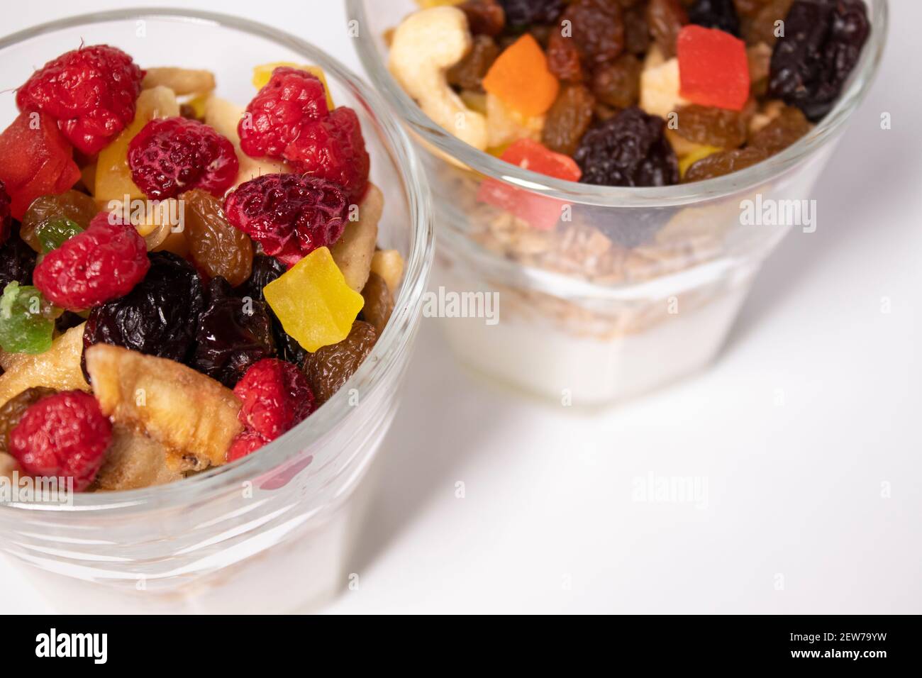 Müsli Dessert mit Joghurt und kandierten oder getrockneten Früchten mit Himbeeren auf der Oberseite in Glas isoliert auf weißem Hintergrund. Frühstück Müsli Stockfoto