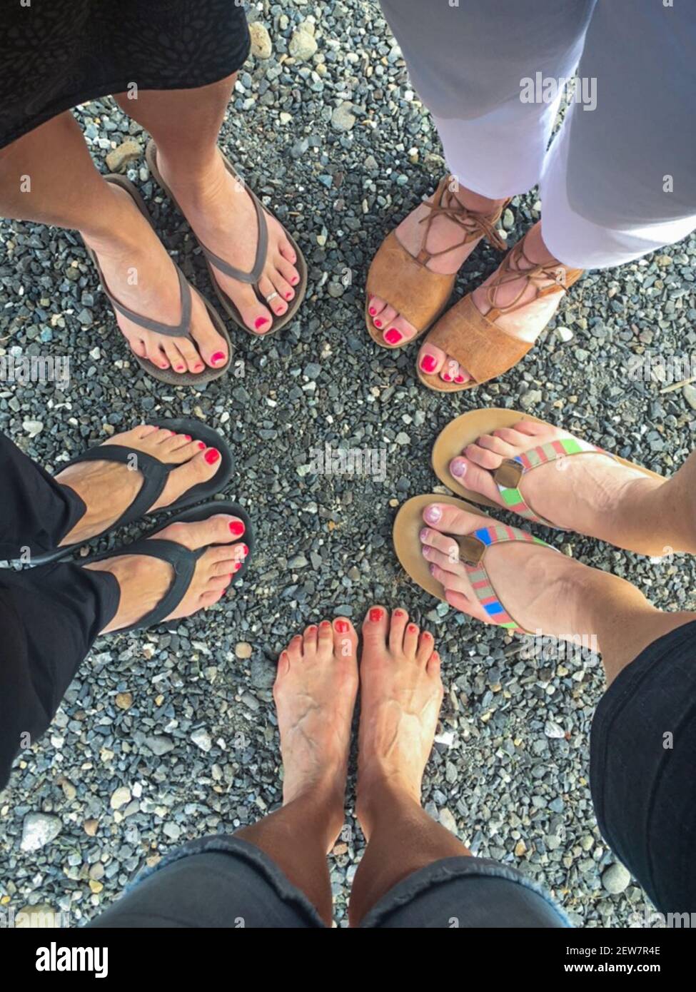 Freunde barfuß Draufsicht. Freunde mittleren Alters bilden einen Kreis mit ihren Füßen. Barfuß und Sandalen. Konzept Freunde, Freundschaft, Vielfalt, anders. Stockfoto