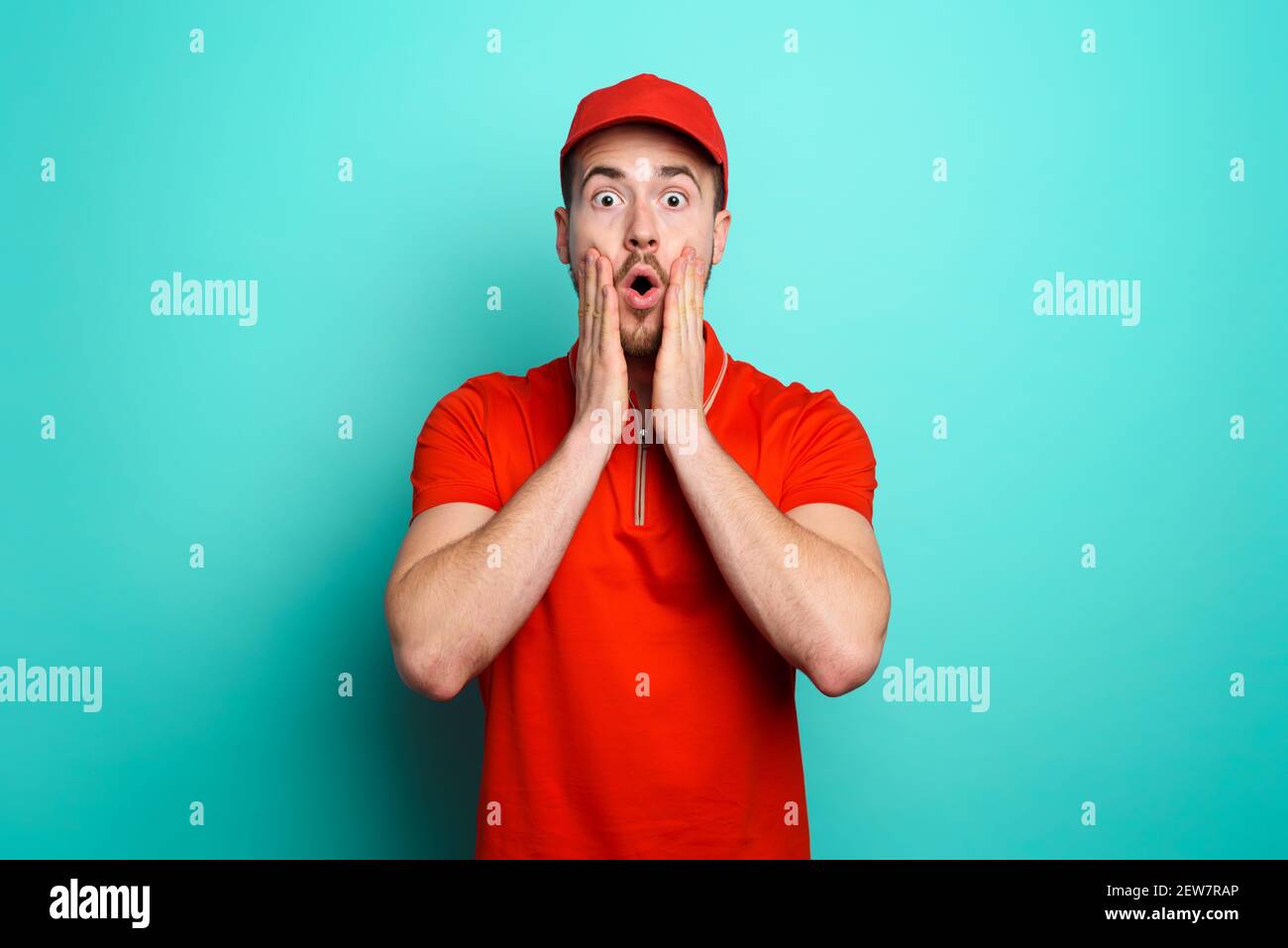 Kurier mit einem wunderten Ausdruck über eine große Förderung. Cyan Hintergrund Stockfoto