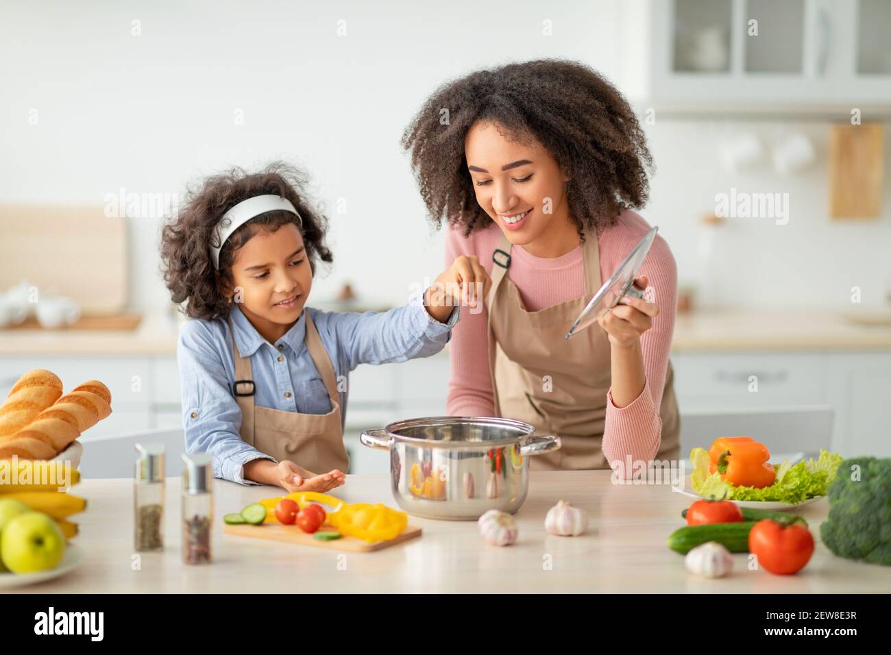 afroamerikanische Mutter lehrt Tochter, wie man Suppe vorzubereiten Stockfoto