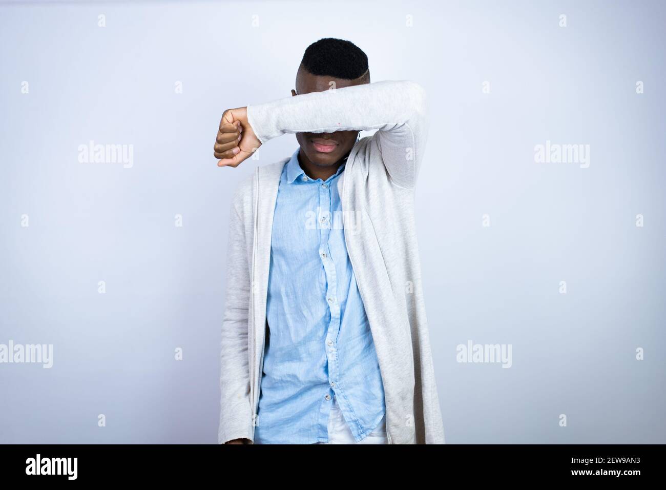 Junger schöner afroamerikanischer Mann trägt lässige Kleidung, die Augen mit Arm lächelnd fröhlich und lustig bedeckt. Blindes Konzept. Stockfoto