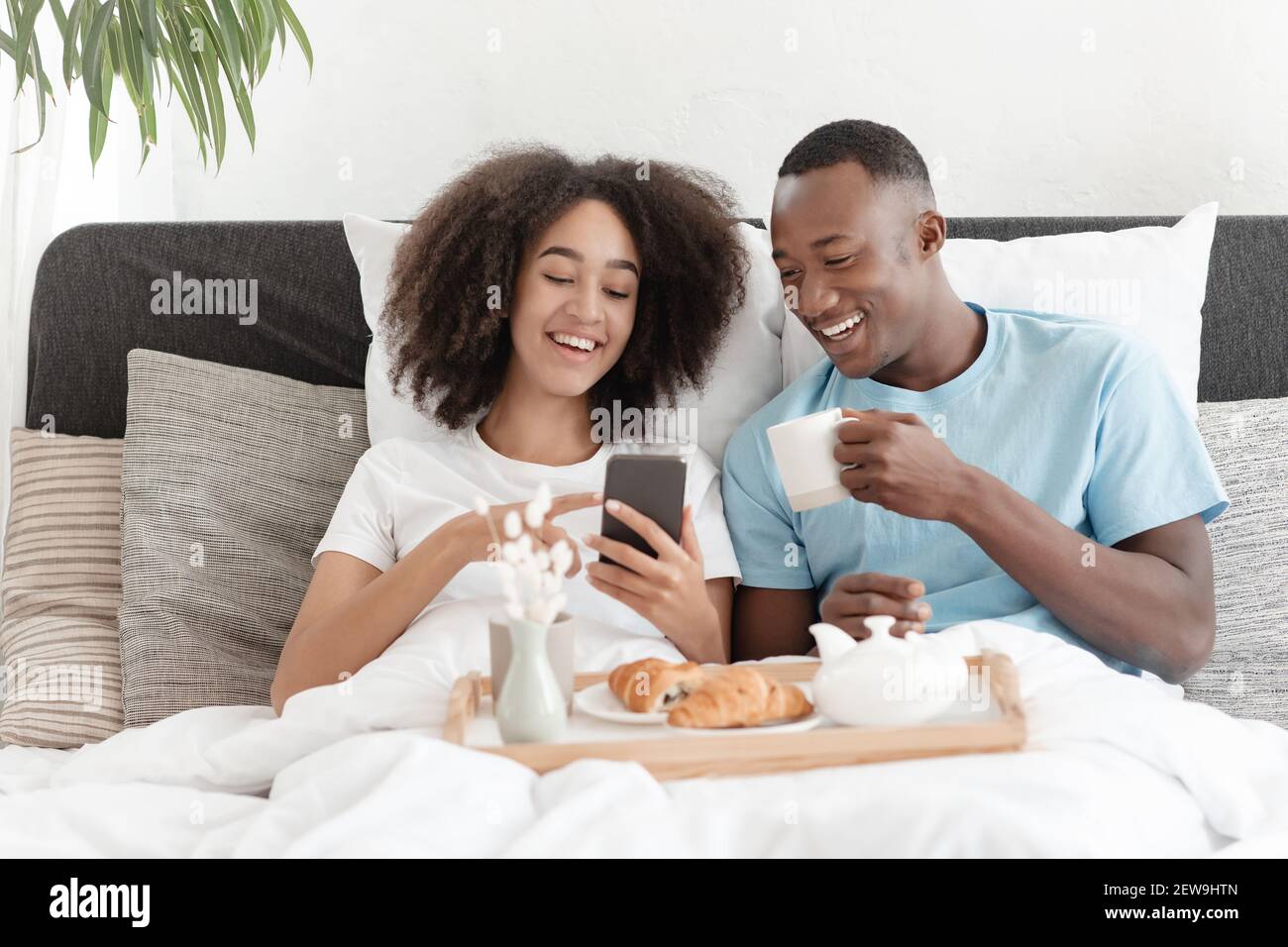 Lesen Sie Nachrichten, soziale Netzwerke, tolles Angebot und Werbung beim Frühstück im Bett Stockfoto