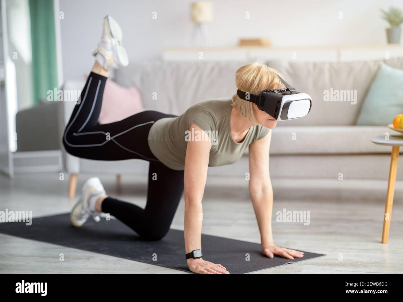 Sport und Virtual Reality Konzept. Ältere Frau im VR-Headset Training zu Hause Stockfoto