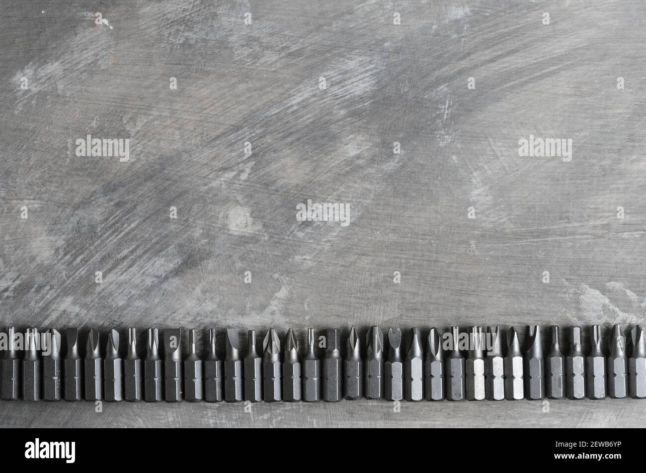 Schraubendreherbits für verschiedene Schlitze, die in einer Reihe auf einer grauen Betonoberfläche angeordnet sind. Stockfoto