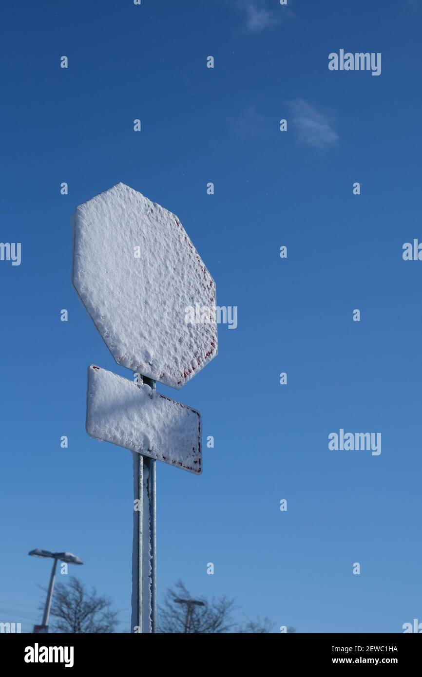 Eine Schneeschicht bedeckt das Gesicht eines Stoppschildes nach einem Wintersturm. Stockfoto
