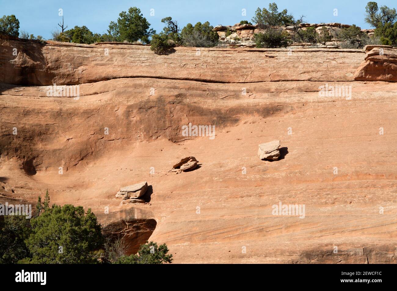 Drei gefallene Steine balancieren auf einem Schräghang im Colorado National Monument in der Nähe von Grand Junction, Colorado USA. Die Schichten der Klippen können sho Stockfoto