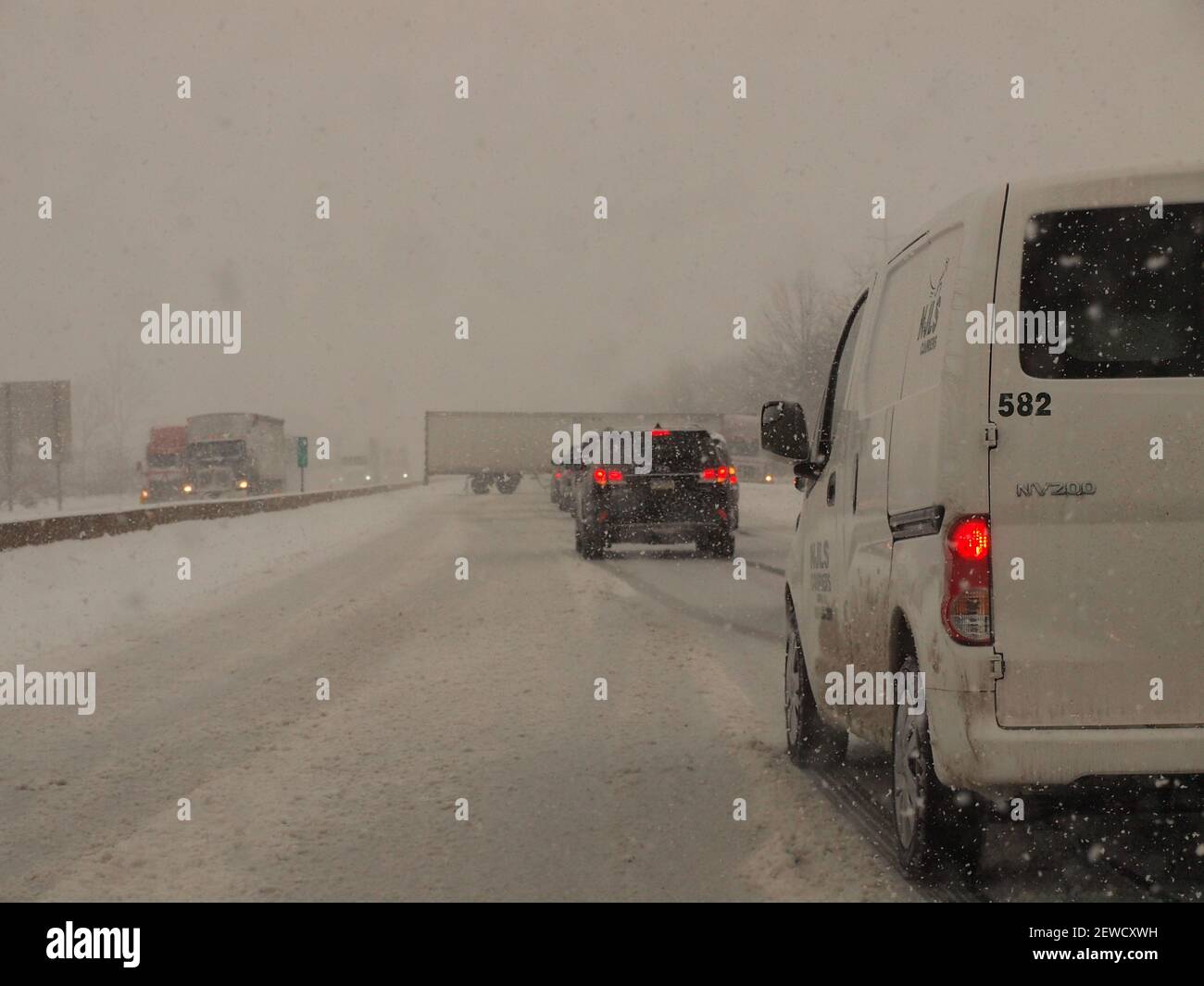 Heftiger Schnee und ein Zuganhänger mit einem Pressmesser auf einer amerikanischen Autobahn, was zu erheblichen Verzögerungen führte. Stockfoto