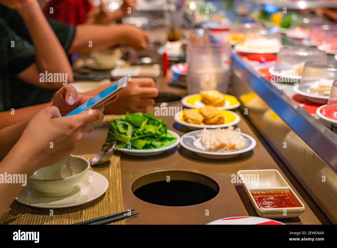 Menschen, die Smartphone beim Essen in Förderband Sushi-Restaurant Stockfoto