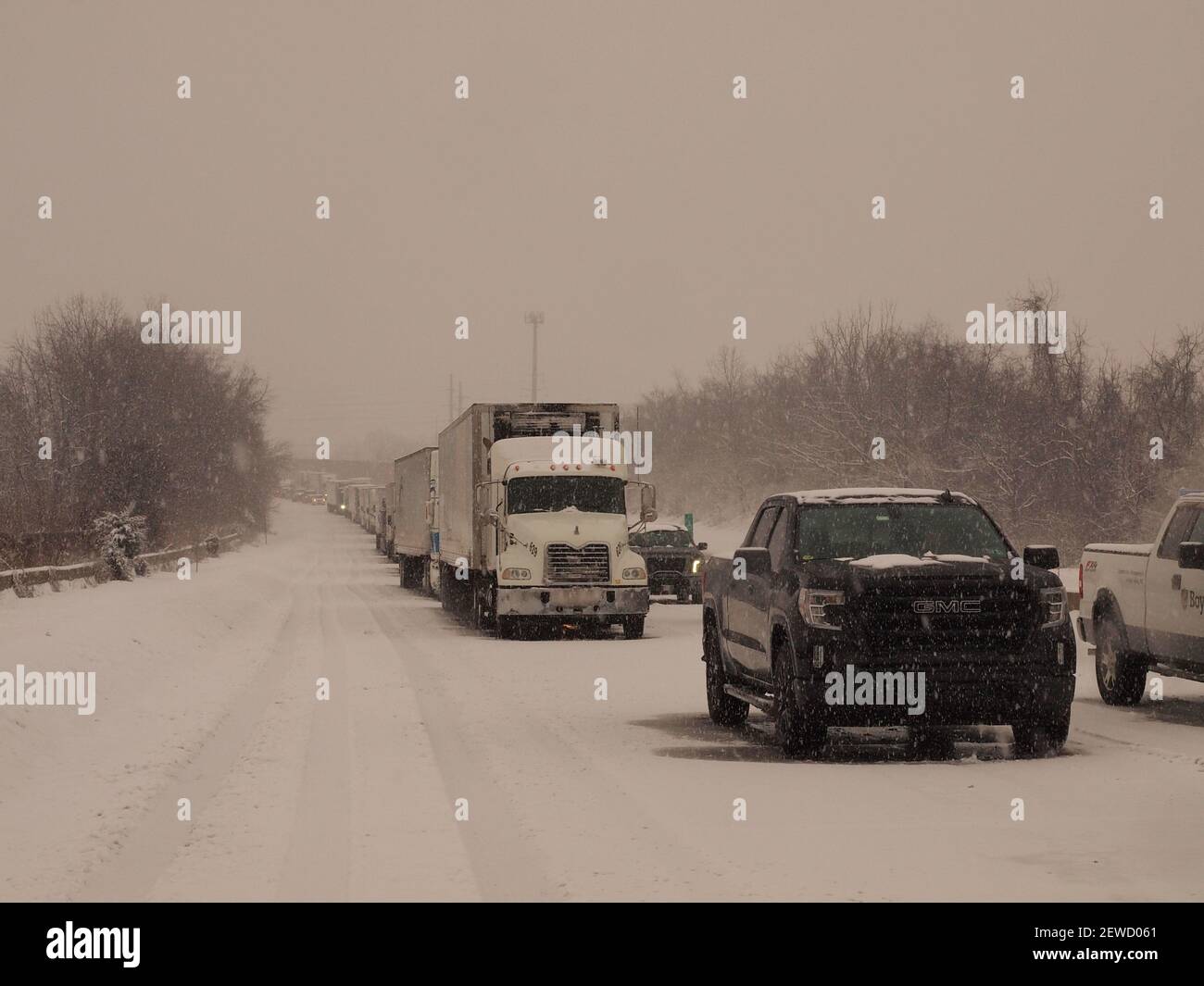 Heftiger Schnee und ein Zuganhänger mit einem Pressmesser auf einer amerikanischen Autobahn, was zu erheblichen Verzögerungen führte. Stockfoto