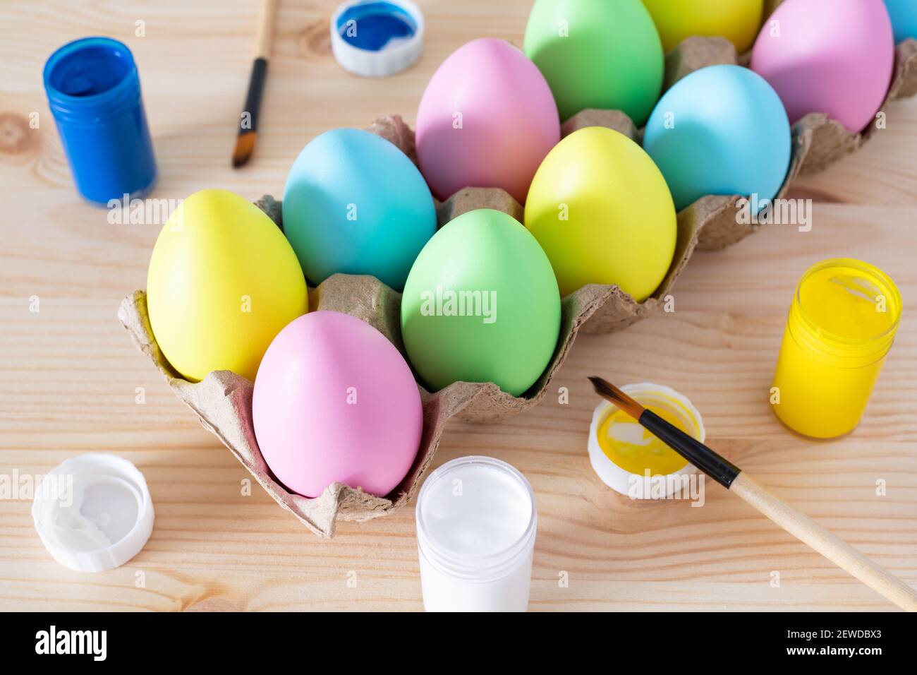 Ostereier und farbige Farben mit Pinsel auf dem Tisch. Osterhandwerk-Konzept. Stockfoto
