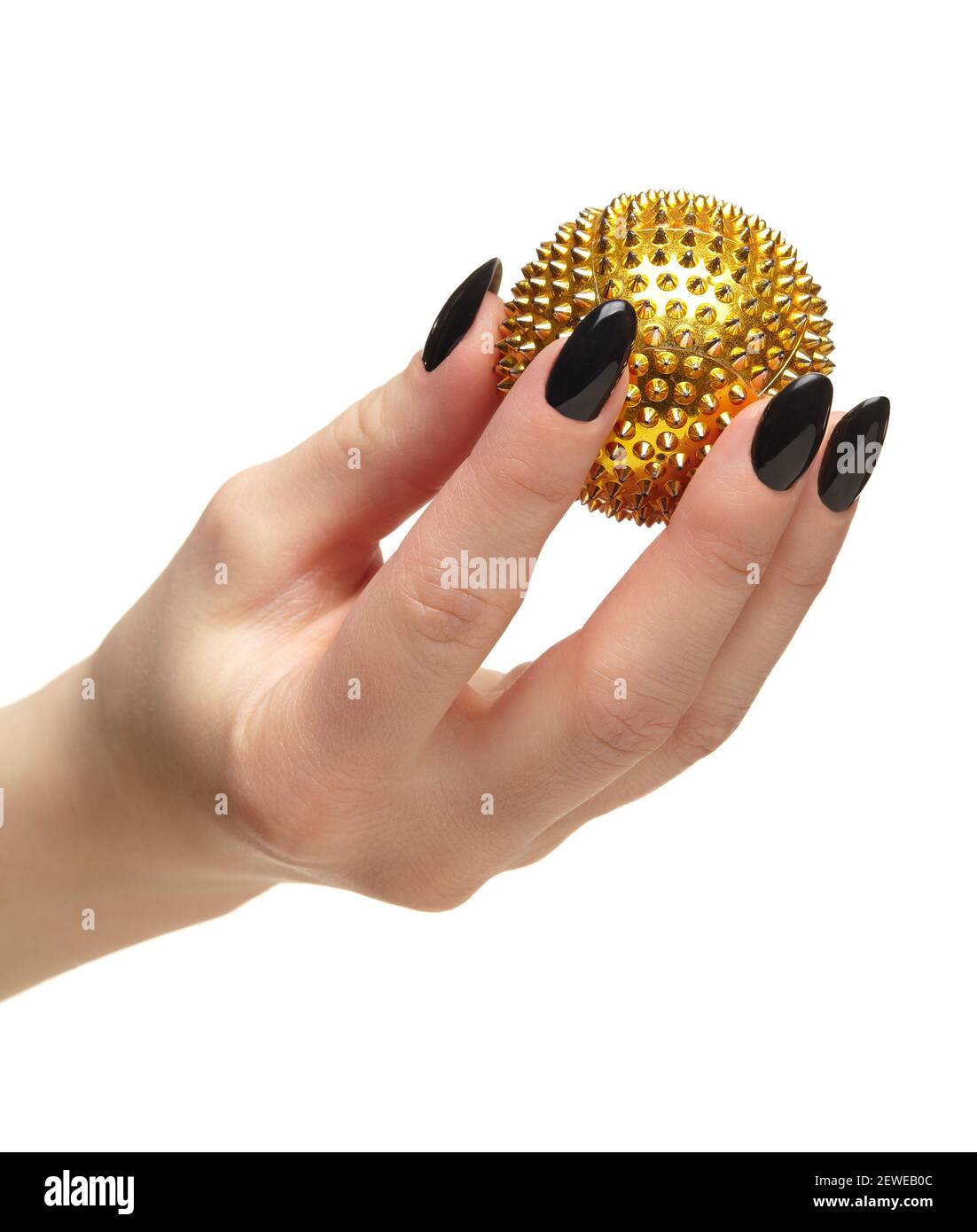 Weibliche Hand mit schwarzen Nägeln Maniküre und goldenen Spikes Massage Ball in den Fingern. Isoliert auf weißem Hintergrund. Stockfoto
