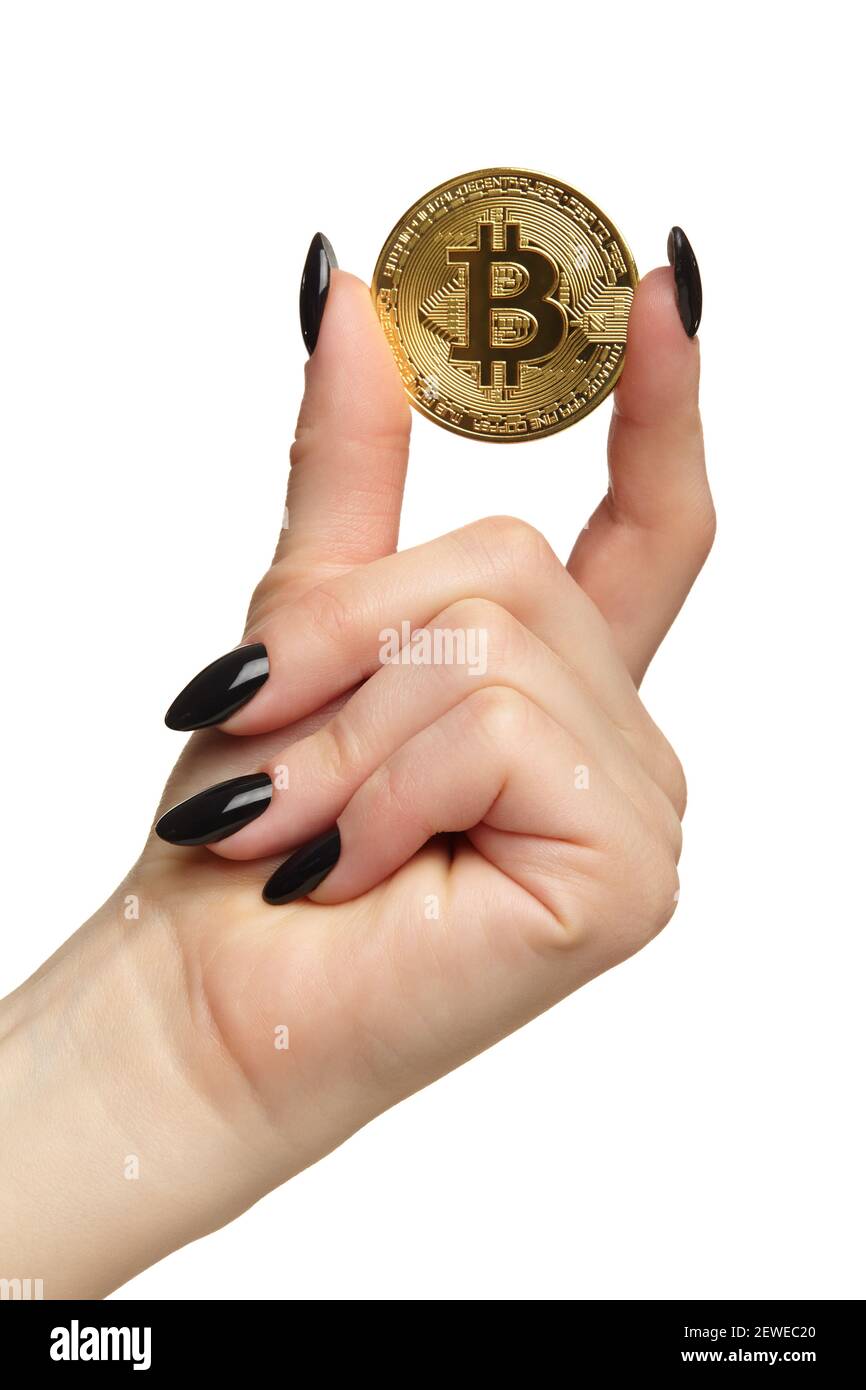 Weibliche Hand mit schwarzen Nägeln Maniküre und goldenen Bitcoin in den Fingern. Isoliert auf weißem Hintergrund. Digitales Kryptowährungskonzept. Stockfoto