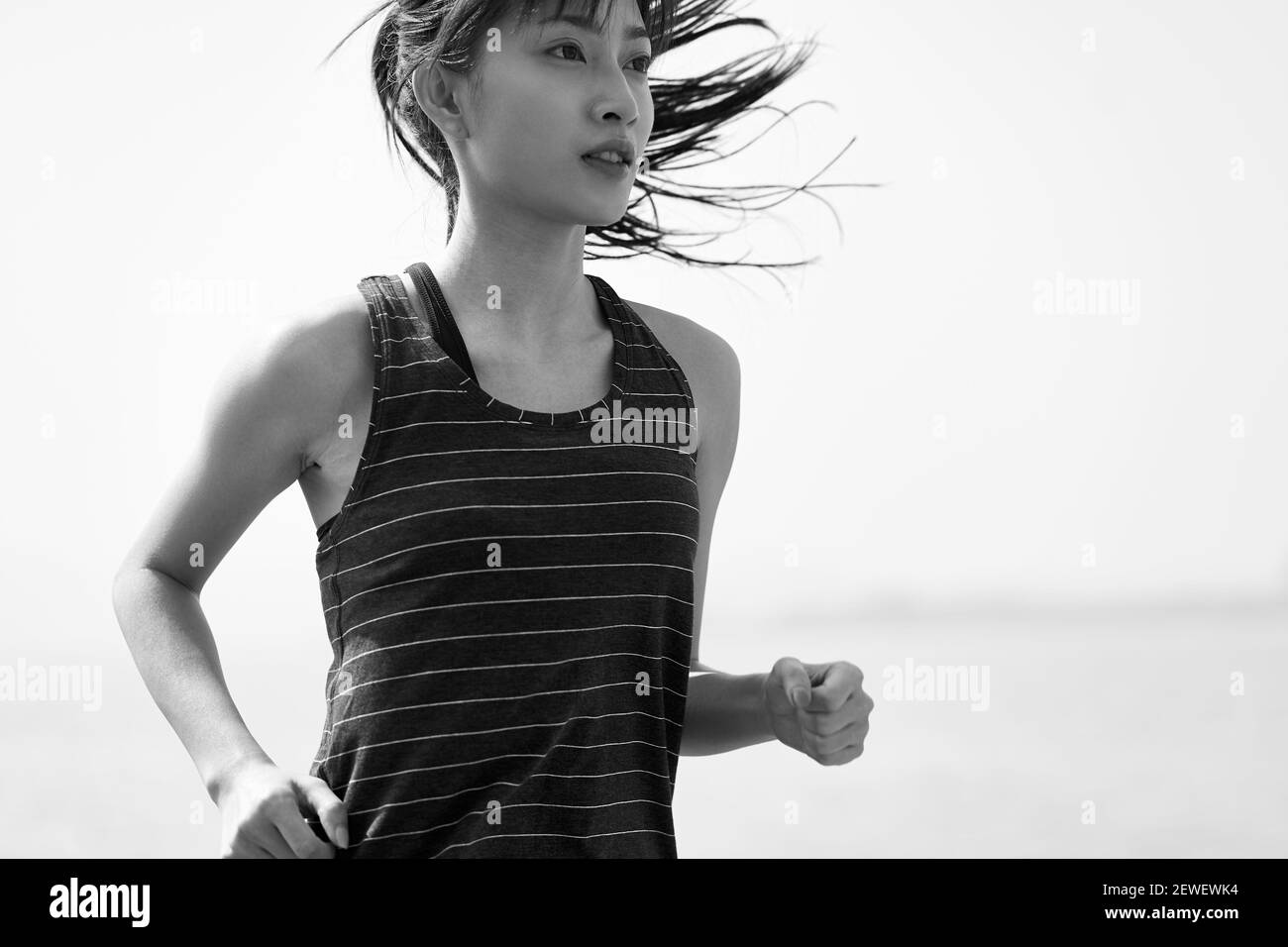 Junge asiatische Frau Joggerin läuft am Meer, schwarz und weiß Stockfoto