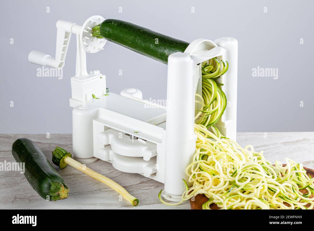 Nahaufnahme isoliertes Bild eines handbetriebenen Gemüseschneidemaschine aus Kunststoff, Spiralizer auf Küchenarbeitsplatten. Bild zeigt Zucchini Nudeln gemacht vorbei Stockfoto