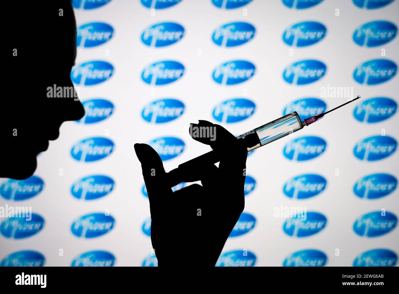 Eine Frau hält eine Nadel vor einem Pfizer-Logo auf diesem Foto. Stockfoto