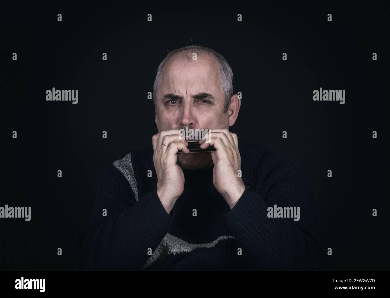 Nizza Low-Key-Porträt von reifen kaukasischen Mann spielen Mund Orgel Stockfoto