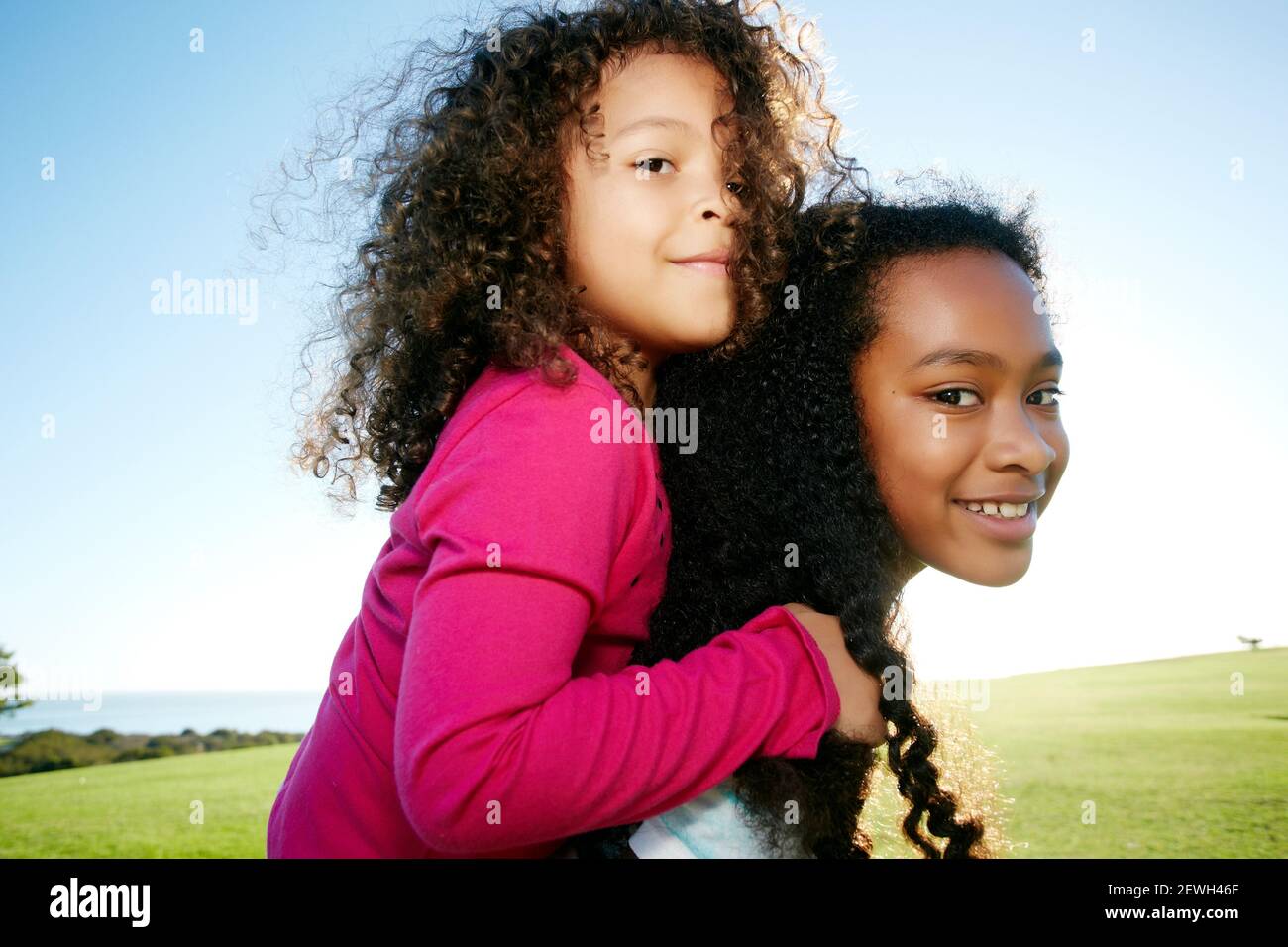 Junge gemischte Rasse Mädchen geben eine jüngere Schwester ein Huckepack Stockfoto