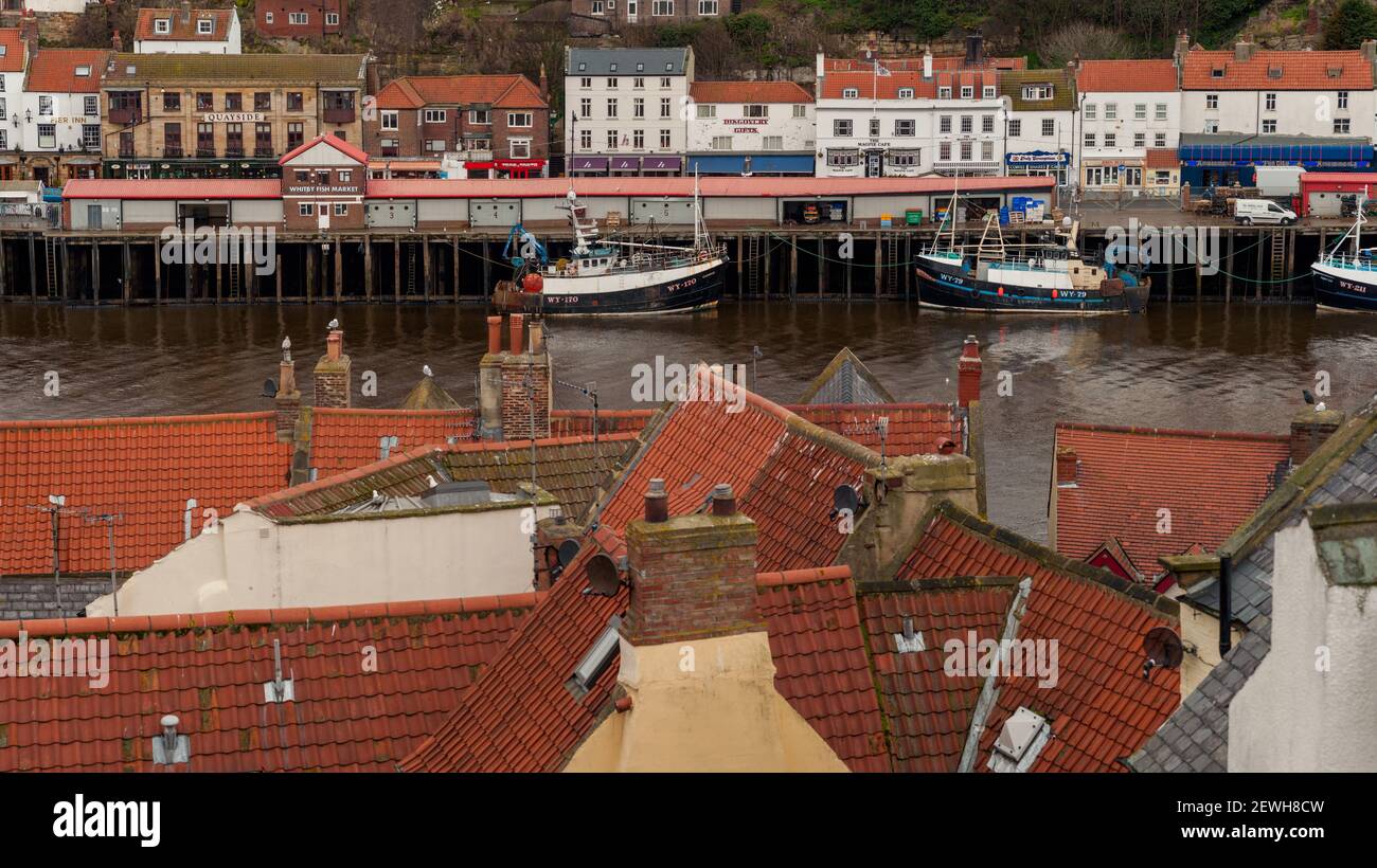 WHITBY, NORTH YORKSHIRE, UK - 15. MÄRZ 2010: Trawler im Hafen über rote Pantile Dächer Stockfoto