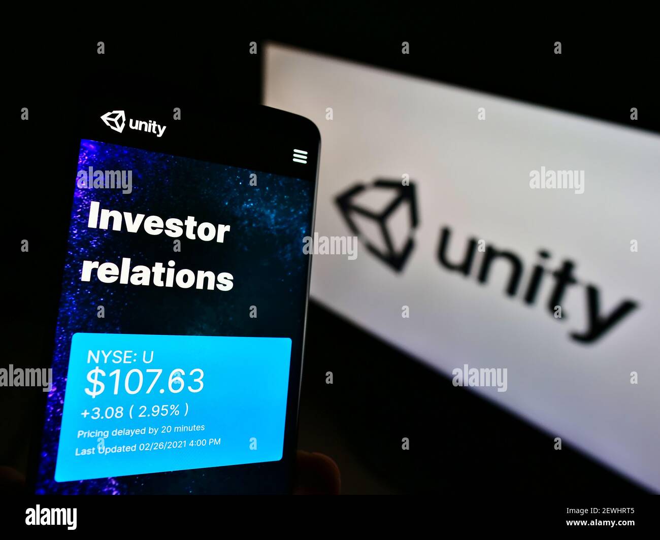 Person, die Mobiltelefon mit Website der US-Videospielfirma Unity Software Inc. Auf dem Bildschirm vor dem Logo hält. Konzentrieren Sie sich auf das Display des Telefons in der Mitte links. Stockfoto