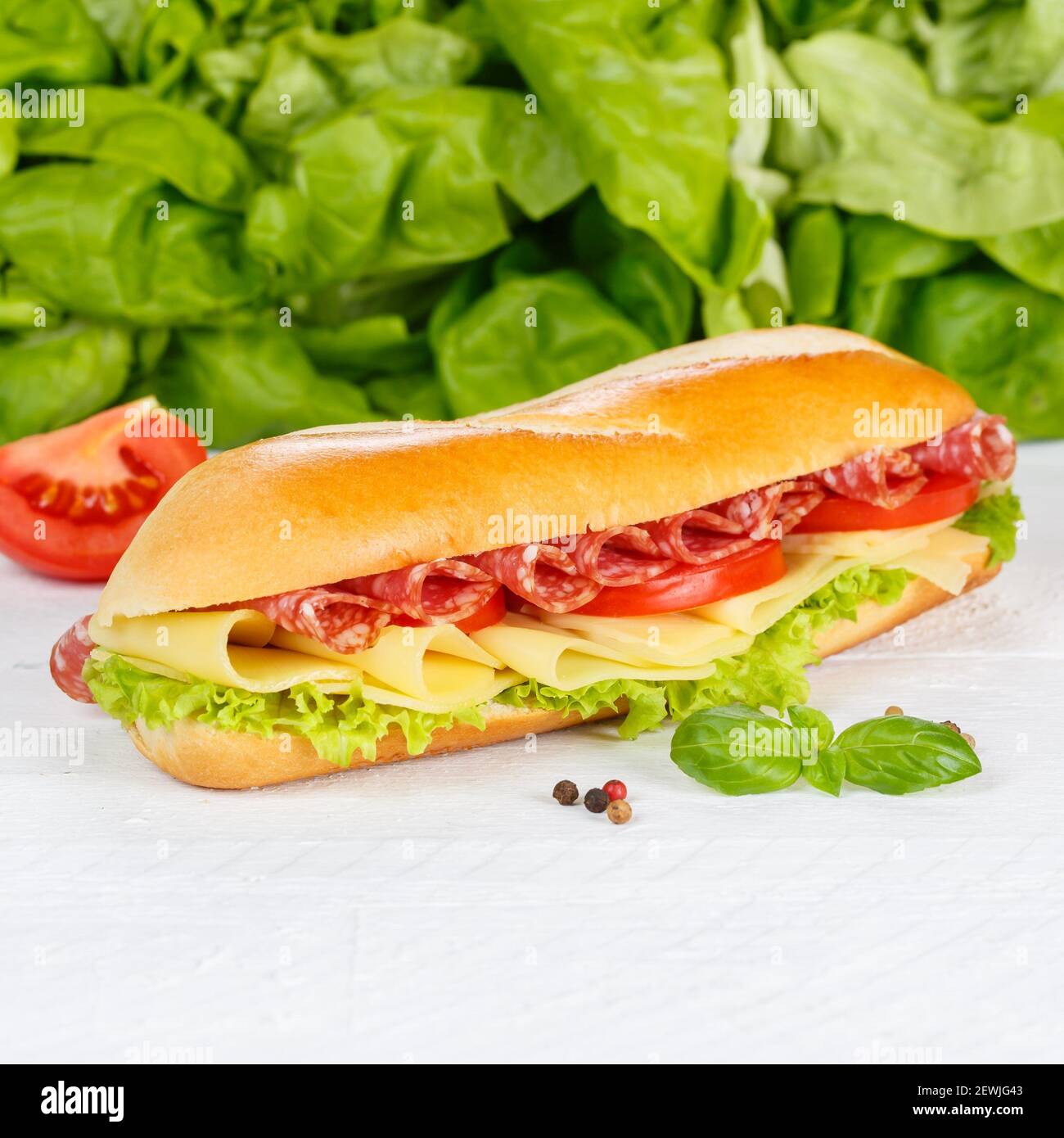 Sub Sandwich Baguette mit Salami Schinken und Käse Quadrat auf Holzbrett Holz. Stockfoto