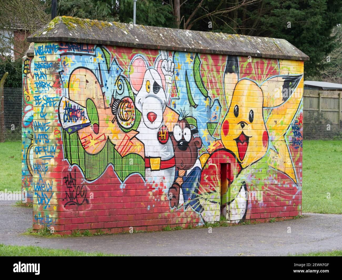 Mit Graffiti bedeckte Ziegelwand auf dem Kinderspielplatz im Greenspace Park, Westbury, Wiltshire, England, Großbritannien. Stockfoto