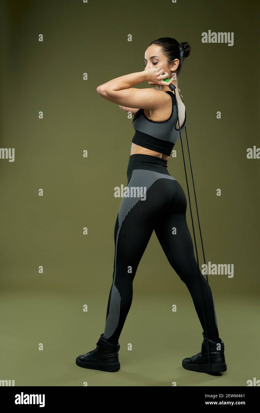 Schöne sportliche Dame in Sportbekleidung mit Springseil beim Training im Studio. Isoliert auf grünem Hintergrund Stockfoto