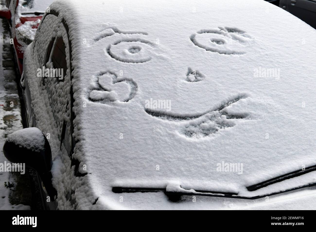 Smiley gezeichnet im Schnee auf der Vorderseite eines Autos in Sartrouville, Yvelines, Frankreich. Stockfoto