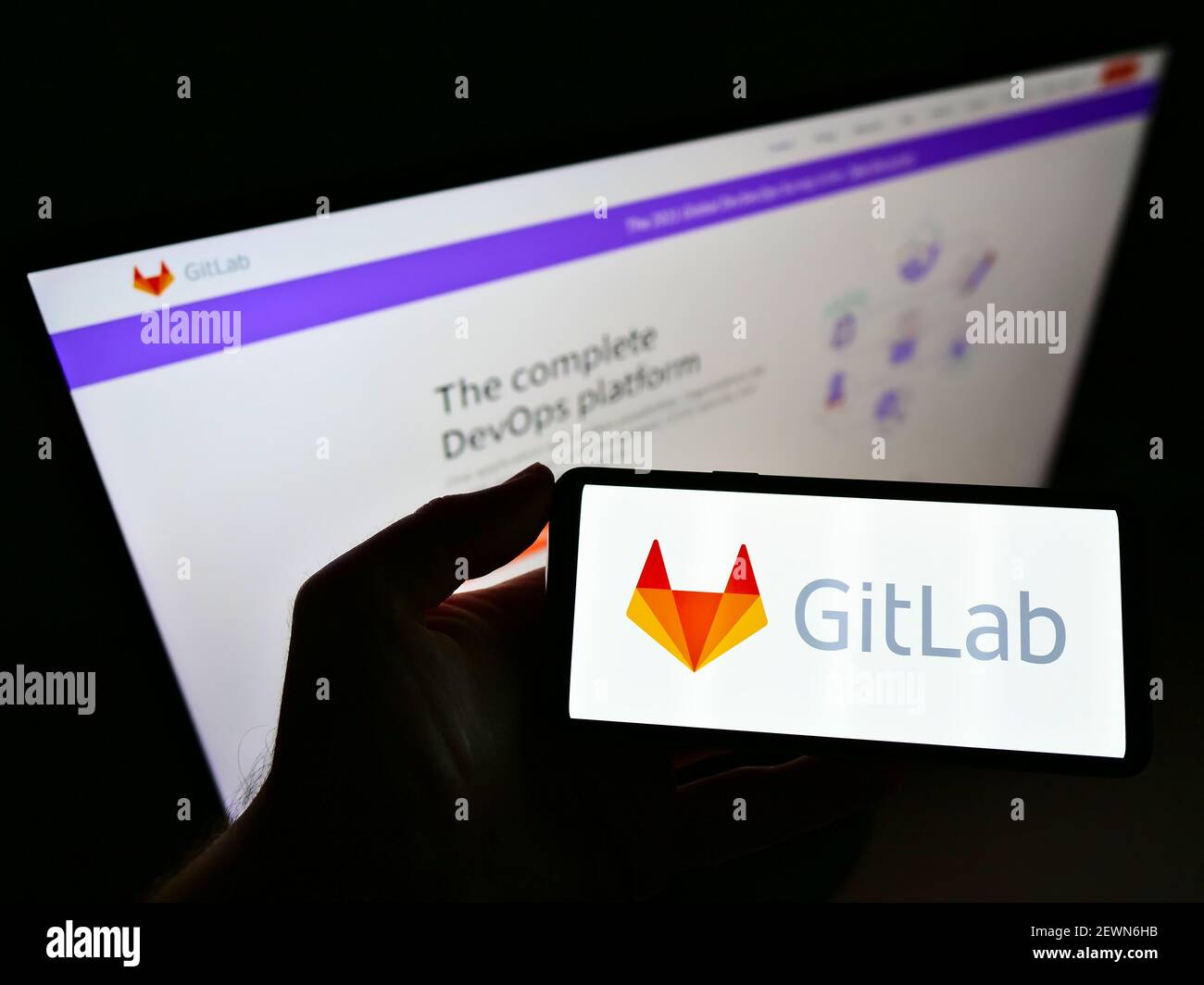 Person mit Smartphone mit Logo der US DevOps Plattform GitLab Inc. Auf dem Bildschirm vor der Website. Konzentrieren Sie sich auf die Telefonanzeige. Nicht modifiziertes Foto. Stockfoto