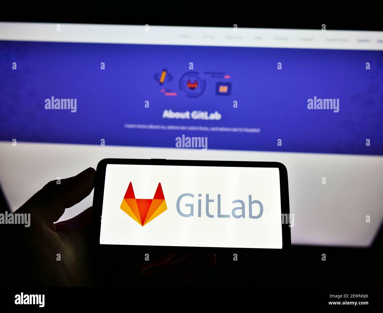 High-Angle-Ansicht der Person halten Handy mit Logo der US DevOps Plattform GitLab Inc. Auf dem Bildschirm vor der Website. Fokus auf Handy-Display. Stockfoto