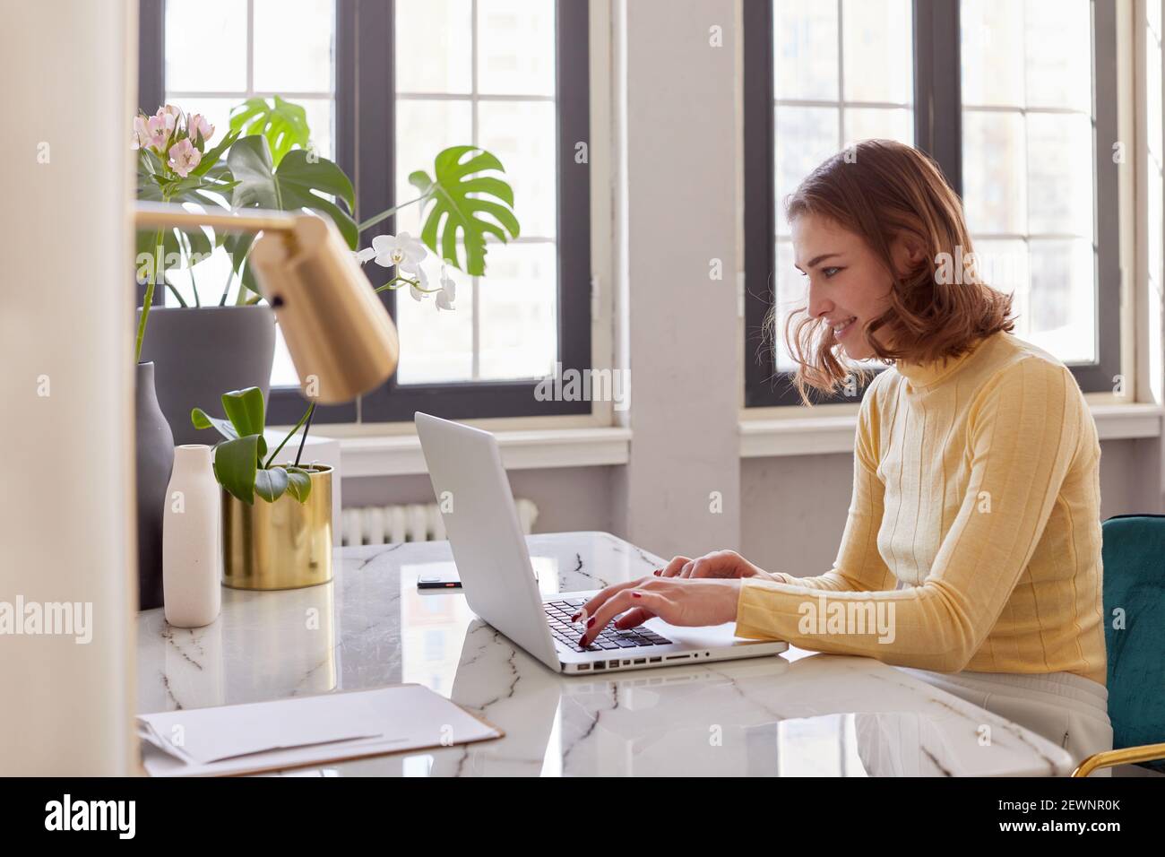 Geschäftsfrau im gelben Rollkragen mit Laptop-Computer und sitzen Am Tisch im Heimbüro Stockfoto