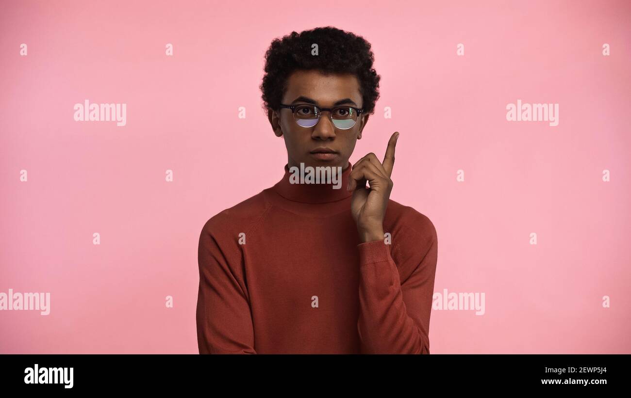 afroamerikanischer Teenager in Rollkragenpullover und Brille mit Idee Isoliert auf rosa Stockfoto