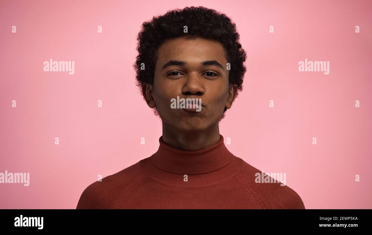 Lockig afroamerikanischen Teenager-Junge in Rollkragen Pullover Pouting Lippen Isoliert auf rosa Stockfoto