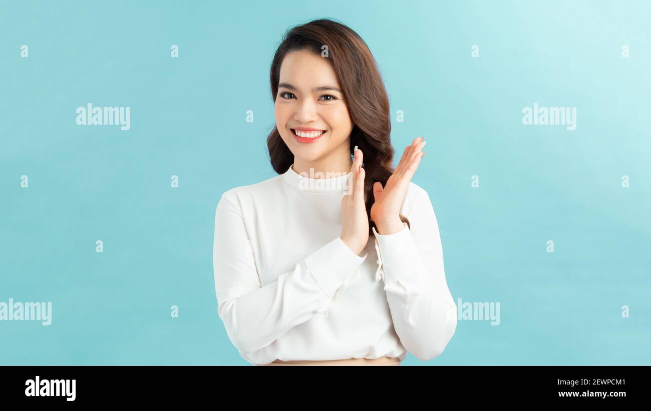 Junge hübsche Frau, glücklich und erfolgreich, lächelnd und klatschende Hände, mit einem Applaus gegen blaue Wand zu gratulieren Stockfoto