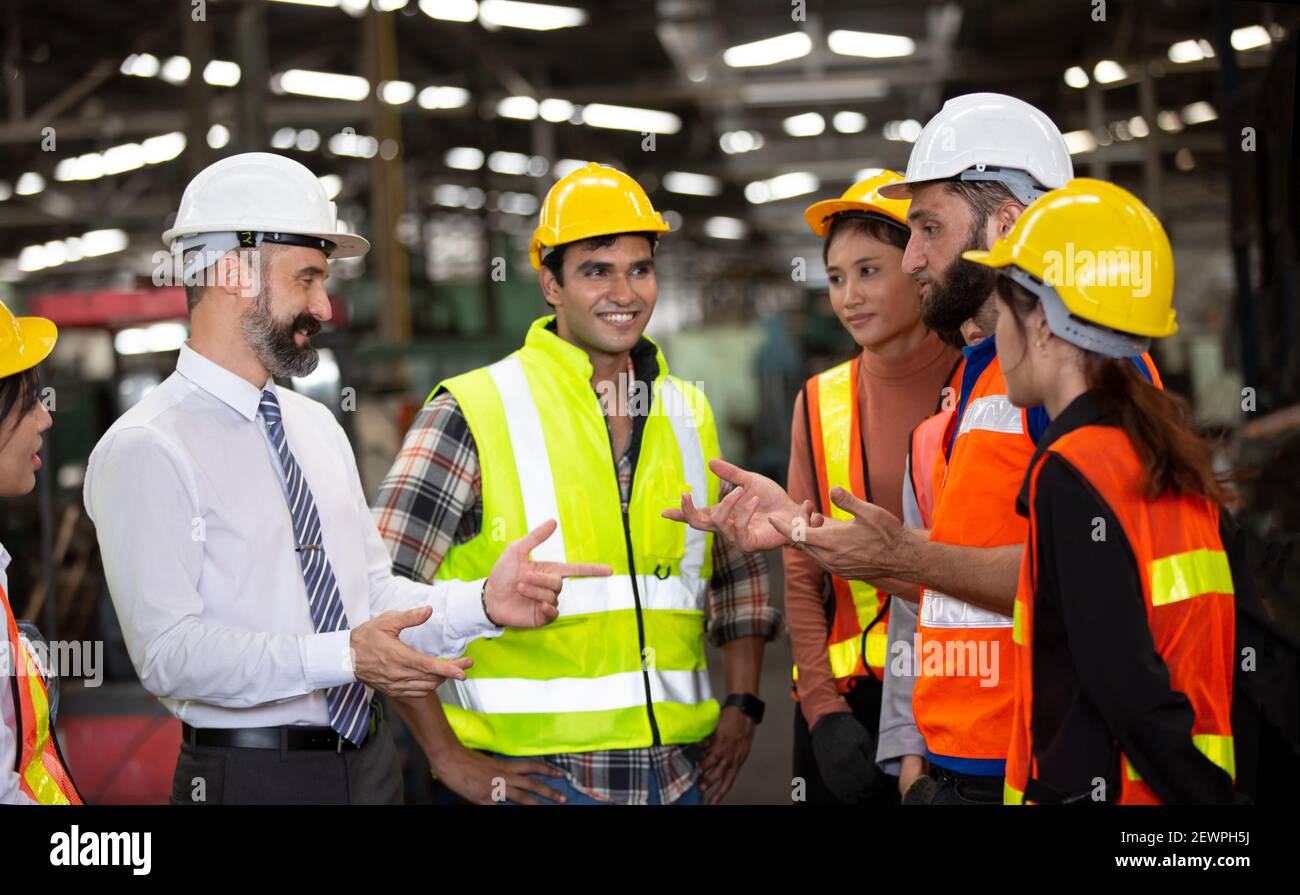 Gruppe der Arbeiter, Wechsel der Arbeiter in der Fabrik, gehen die Menschen in Helmen und Uniformen für ein Industrieunternehmen Stockfoto