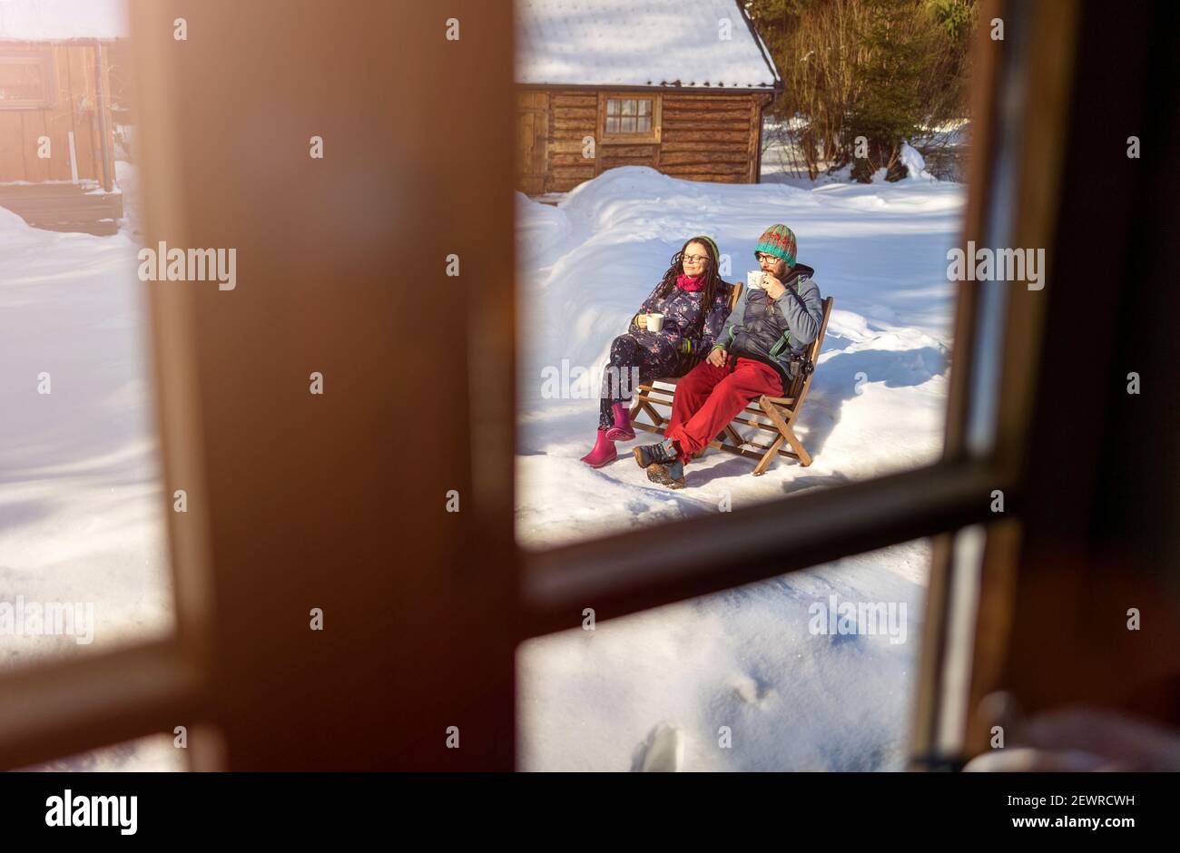 Pärchen genießen den Wintertag mit einer Tasse Heißgetränk Holzhaus Stockfoto
