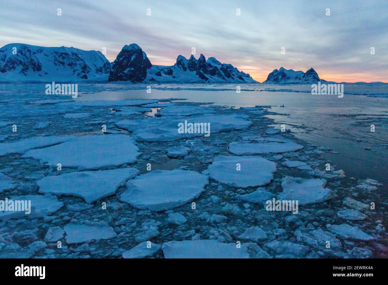 Sonnenaufgang auf schneebedeckten Bergen und dichtem Meereis im Neumayer-Kanal, Palmer-Archipel, Antarktis, Polarregionen Stockfoto