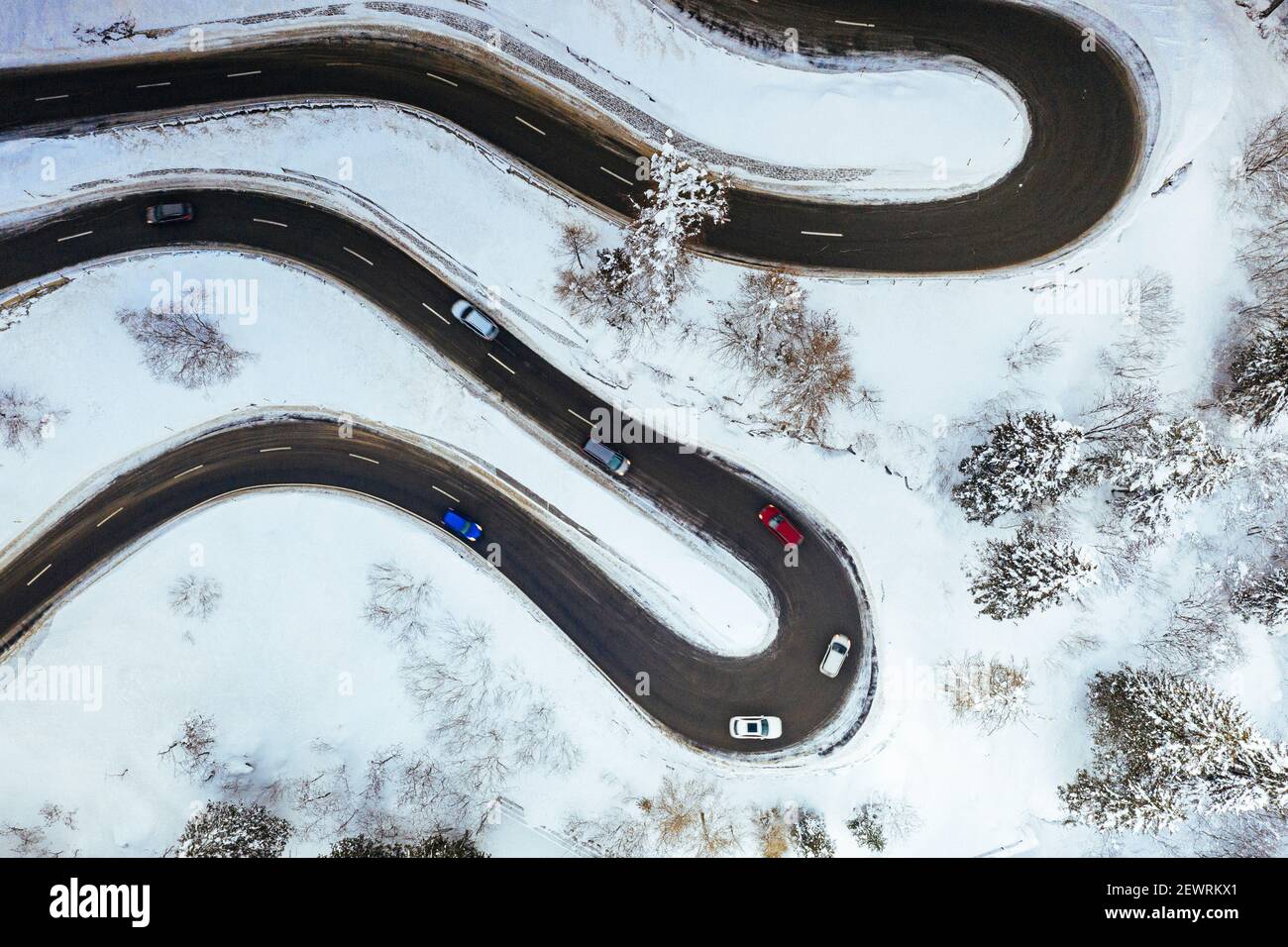 Luftaufnahme von Autos fahren auf Kurven der verschneiten Bergstraße im Winter, Schweiz, Europa Stockfoto