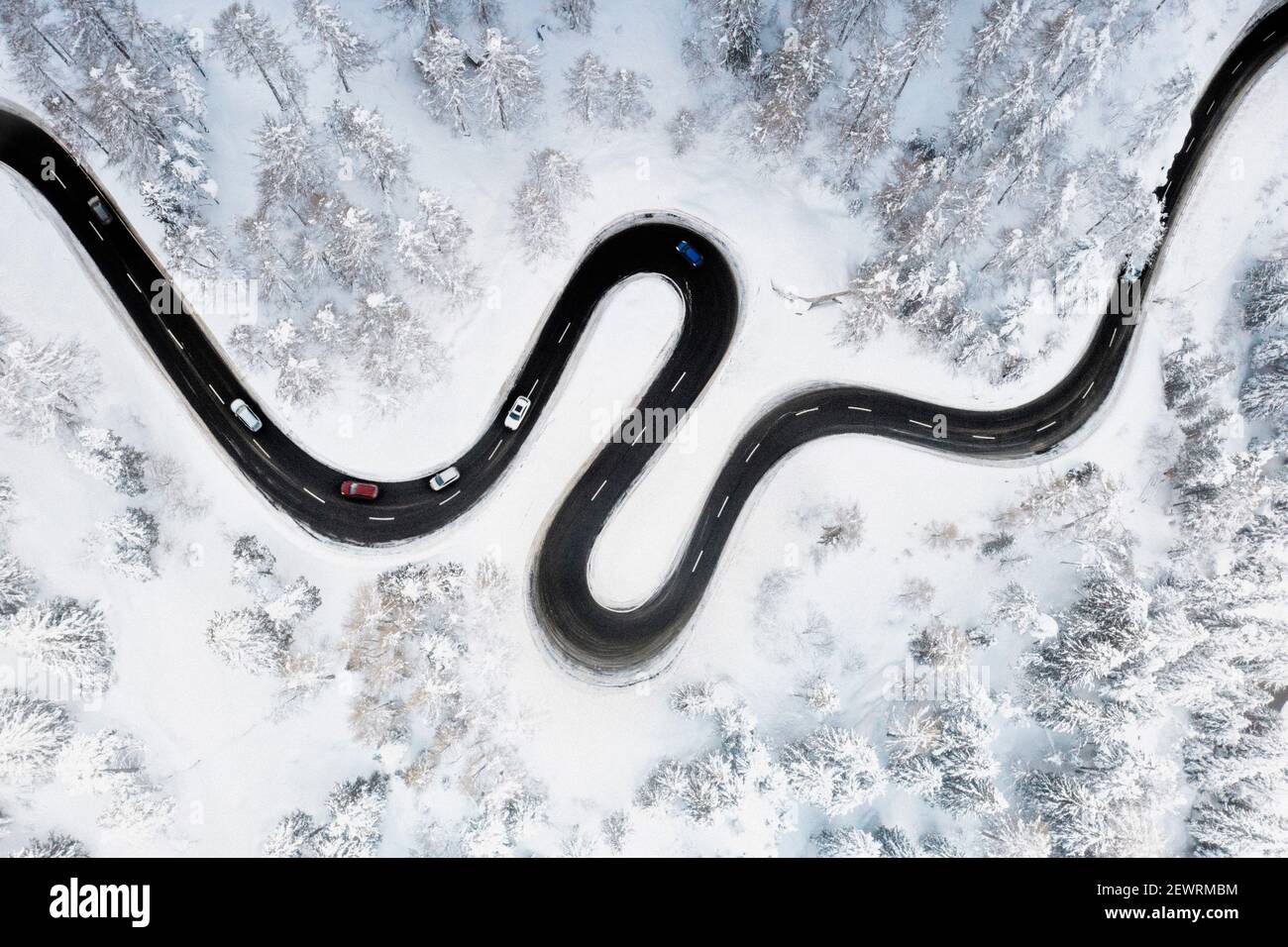 Luftaufnahme der S-förmigen Bergstraße entlang des mit Schnee bedeckten Winterwaldes, Schweiz, Europa Stockfoto