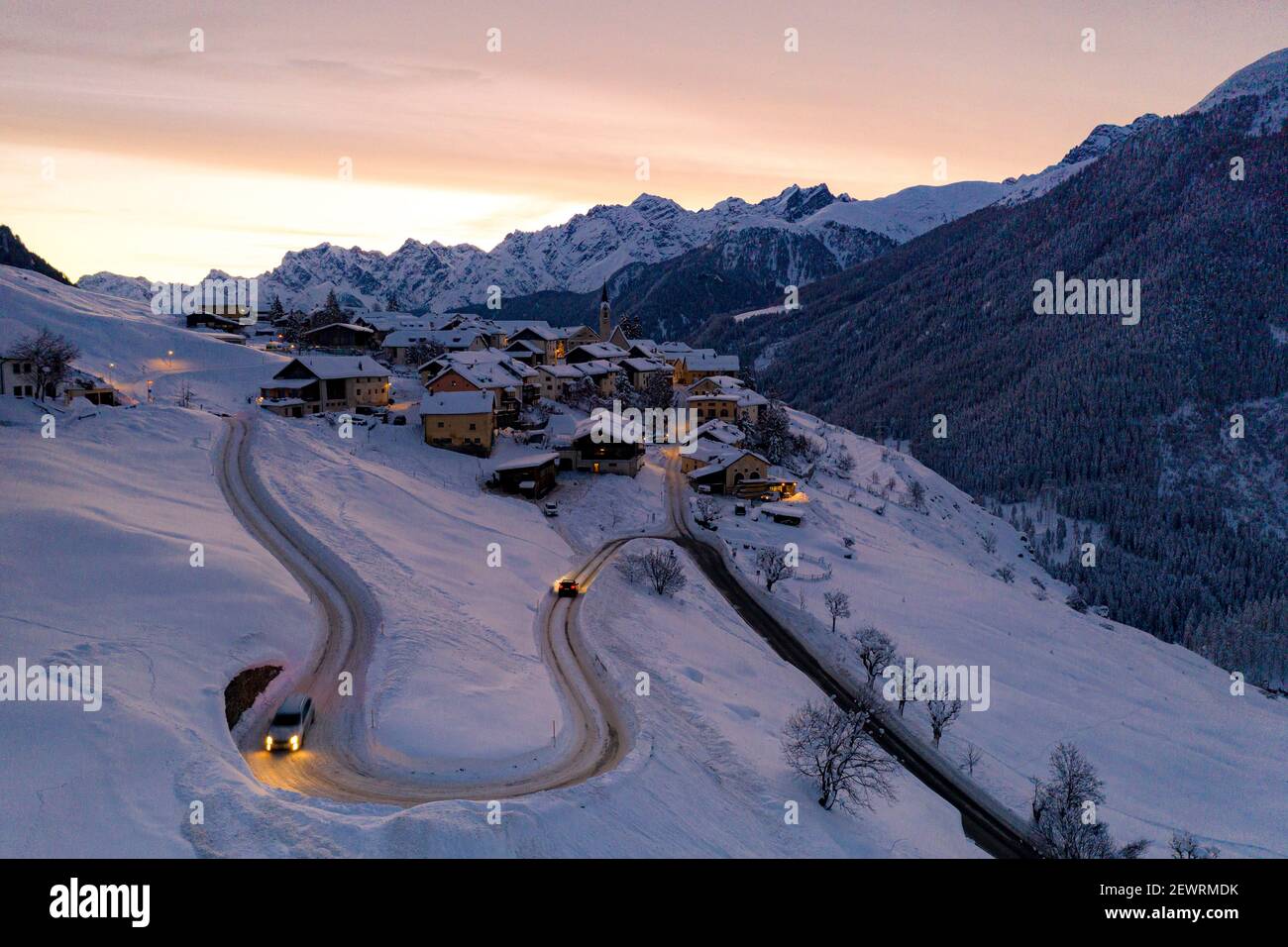 Autos fahren auf Kehren von verschneiten Straßen im Morgengrauen, Guarda, Unterengadin, Graubünden Kanton, Schweiz, Europa Stockfoto