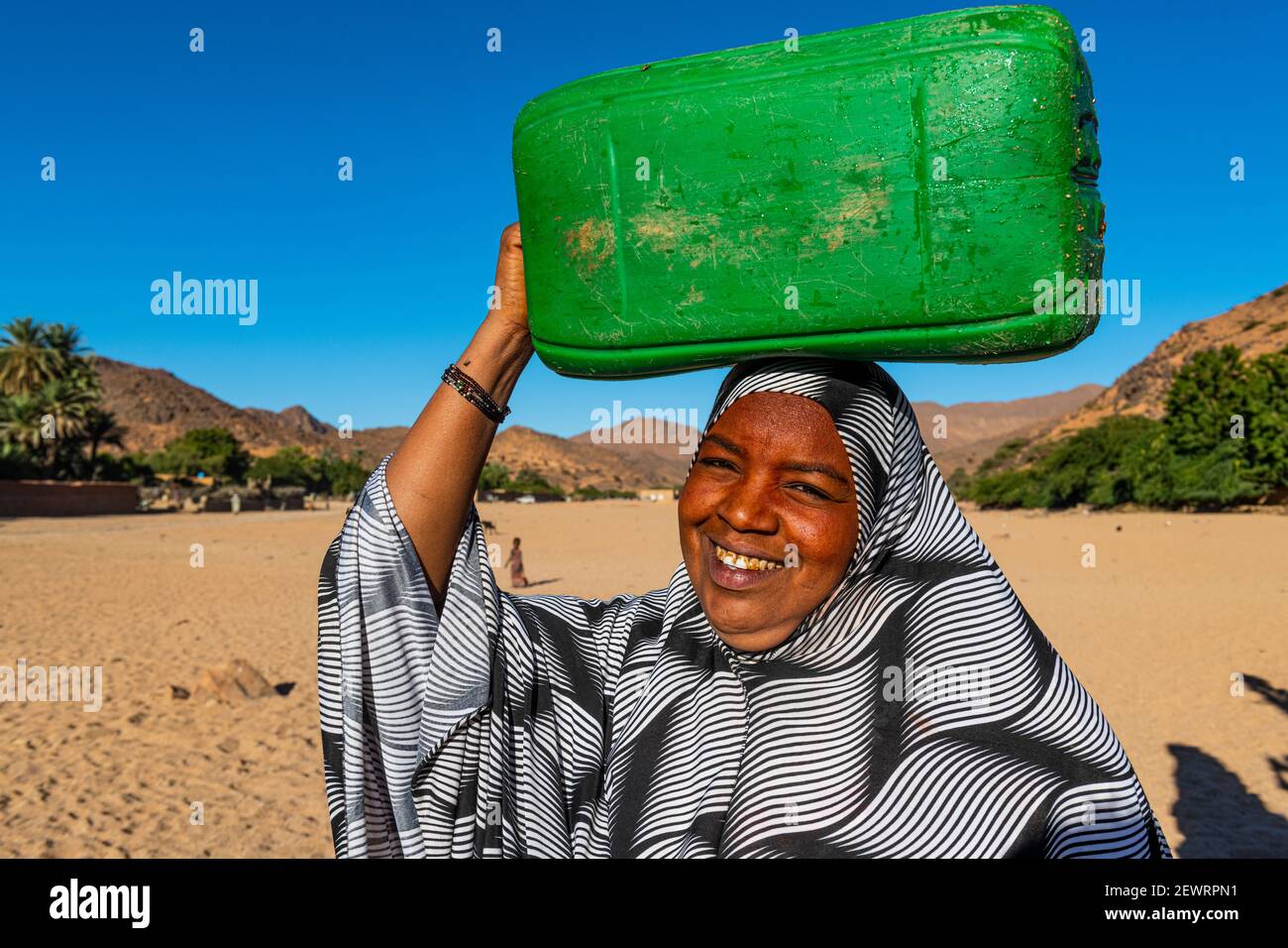 Frau, die einen Wasserbehälter auf dem Kopf trägt, Oase von Timia, Luftberge, Niger, Afrika Stockfoto