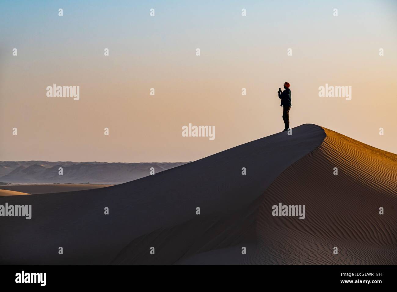 Mann wandern durch die Sanddünen, Dirkou, Djado Plateau, Sahara, Niger, Afrika Stockfoto
