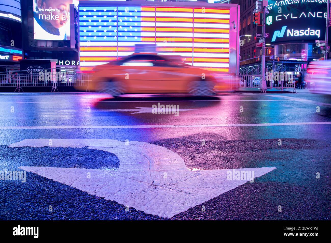 Taxi verschwimmt durch eine beleuchtete Flagge der Vereinigten Staaten von Amerika am Times Square, New York City, Vereinigte Staaten von Amerika, Nordamerika Stockfoto