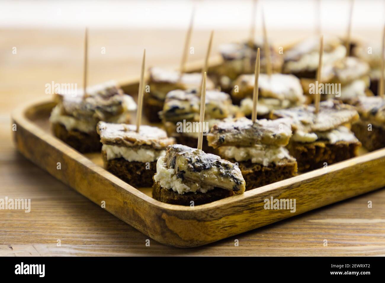 Kleine Vorspeisen mit Fischkonserven und Frischkäse Holztablett auf Tischhintergrund Stockfoto