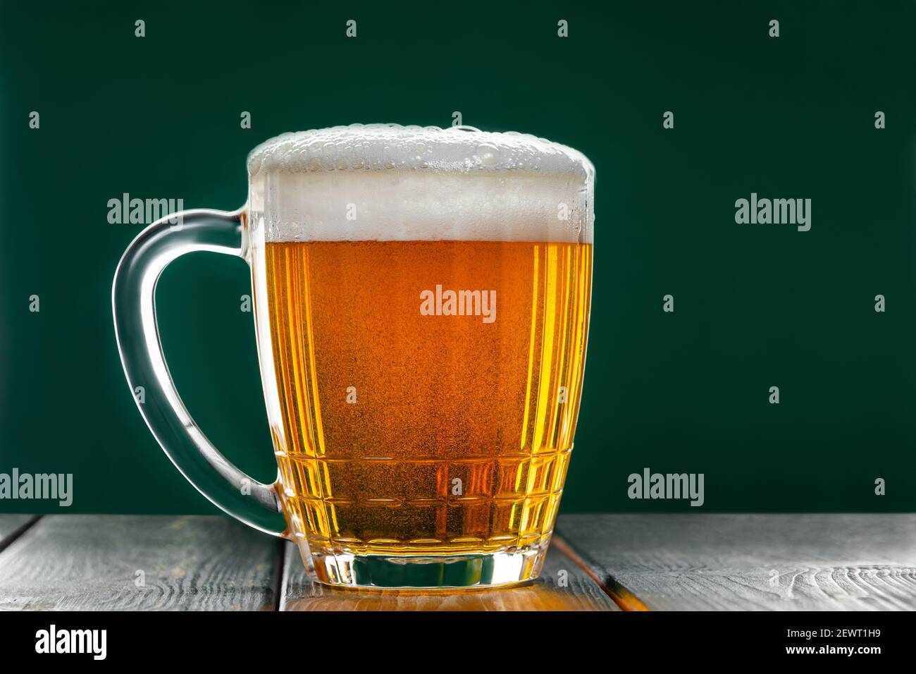 Becher mit traditionellem Irish Pale Ale auf dunkelgrünem Hintergrund. Blasen im Glas Bier. Stockfoto