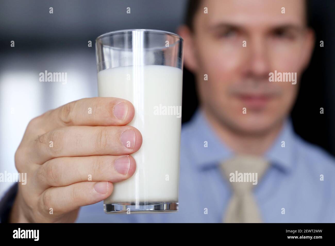 Glas Milch in der männlichen Hand Nahaufnahme, Ernährung und Ernährungskonzept. Glücklicher Mann in Bürokleidung mit einem gesunden Getränk Stockfoto