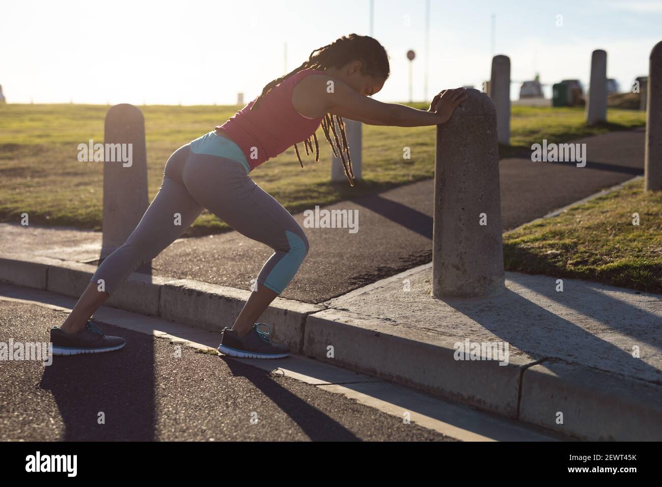 afroamerikanische Frau, die sich auf die Ausübung im Park an der Wand lehnt, Stretching Stockfoto