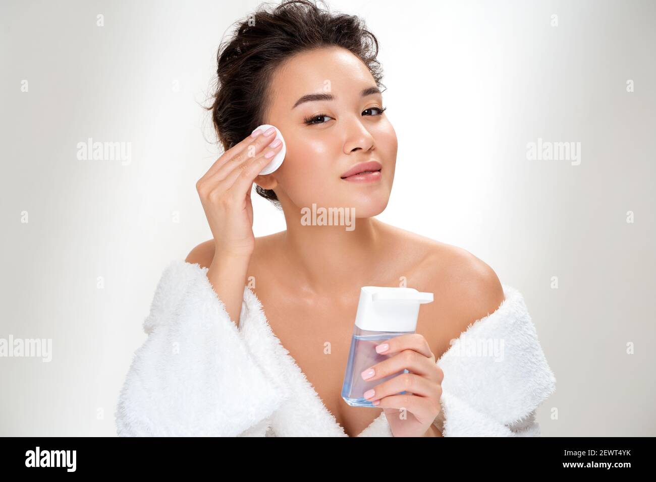 Frau, die Make-up entfernt, hält Wattepads nahe dem Gesicht. Foto von asiatischen Frau mit perfekter Haut auf weißem Hintergrund. Beauty und Hautpflege Konzept Stockfoto