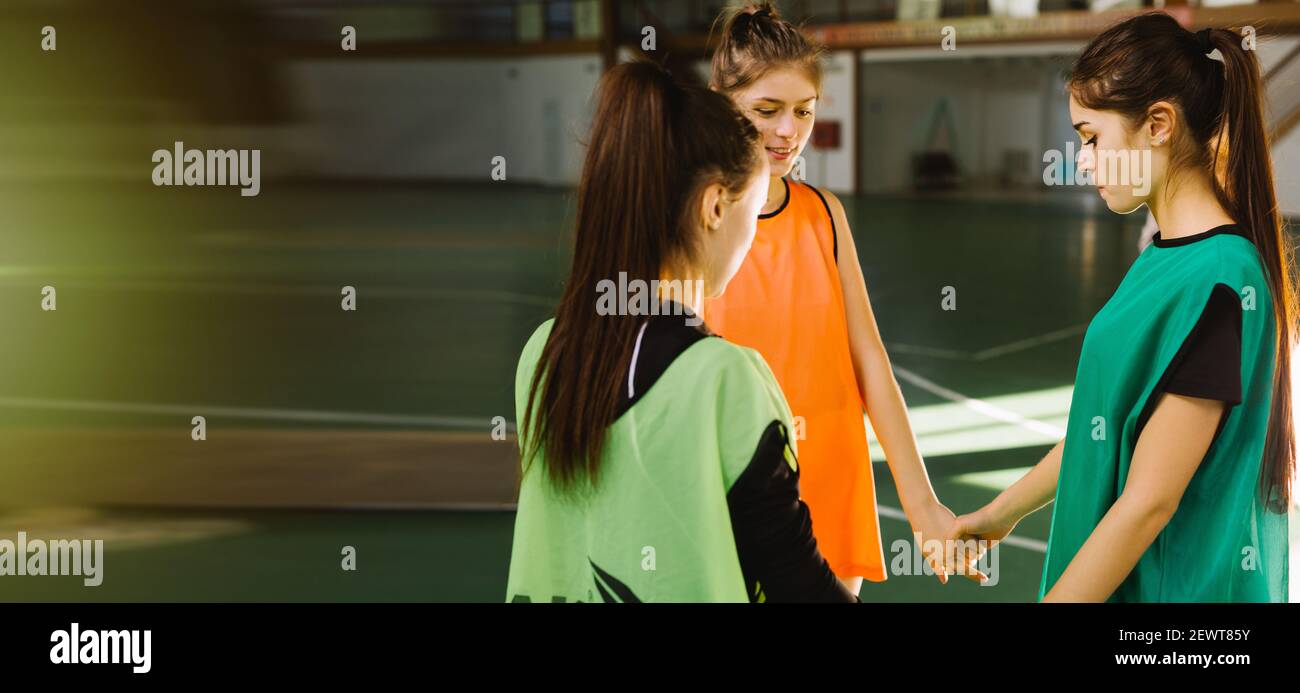 Banner – Langformat. Mannschaftsspielerinnen, die sich vor dem letzten Spiel umarmen. Unterstützer jubeln und beten für ihre Lieblingssportmannschaft. Leere Seite Stockfoto
