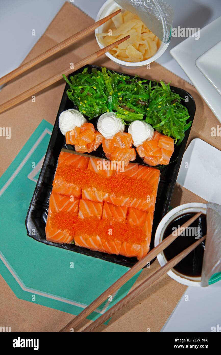Sushi-Set zum Mitnehmen. Sauce, Ingwer in Plastiktüten. Sushi-Sticks. Essen. Blick von oben. Philadelphia. Roter Kaviar, Fischalgen und Meeresfrüchte. Stockfoto