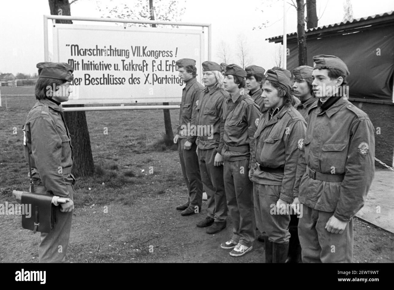 30. November 1981, Sachsen, Delitzsch: Teilnehmer. Unter der Schirmherrschaft des GST finden, wie hier 1982 in Delitzsch, Bezirksmilitärparaden statt. Im Hintergrund der Slogan: 'Marschrichtung VII. Kongress/mit Initiative und Tatkraft für die Erfüllung der Beschlüsse des X. Parteitages! Parteitag!“ Das genaue Datum des Fotos ist nicht bekannt. Foto: Volkmar Heinz/dpa-Zentralbild/ZB Stockfoto